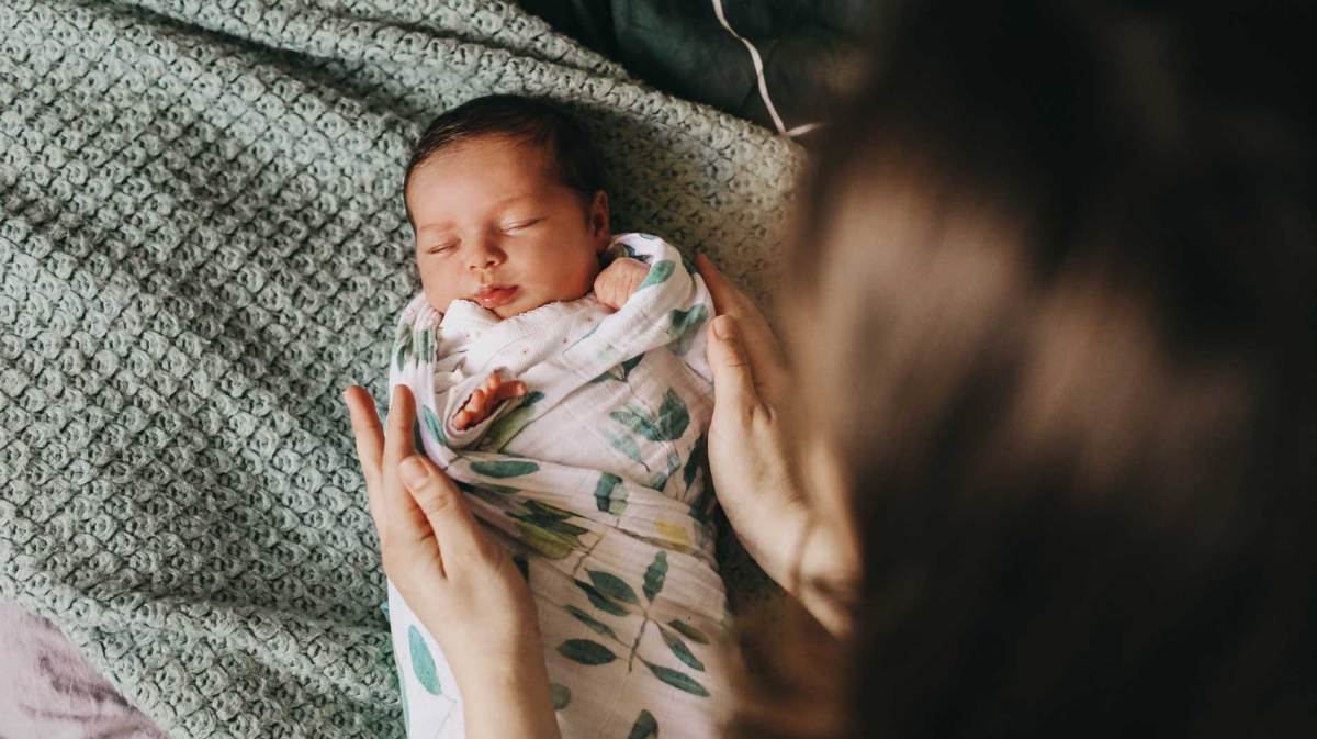 Mutter hat ihr neugeborenes Baby in ein Tuch gewickelt.