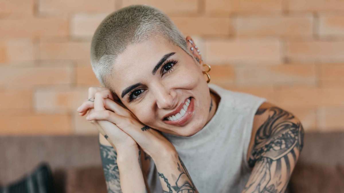 Frau mit Tattoos und blondem Buzzcut.