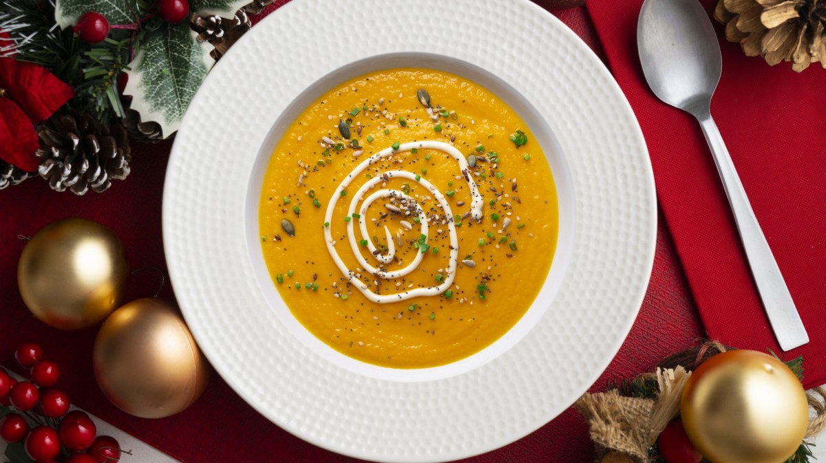 Cremige Karottensuppe in weißem Teller auf weihnachtlich gedeckten Tisch.