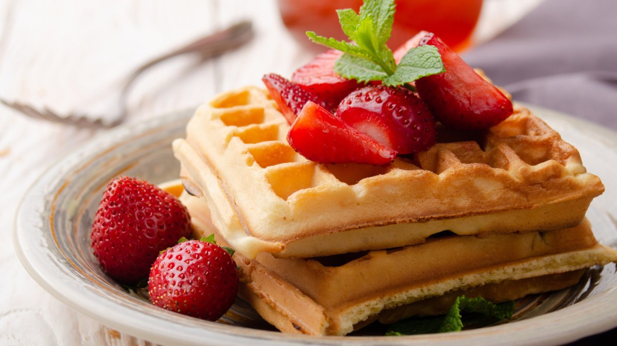 Waffeln auf einem weißen Teller, dazu frische Erdbeeren.