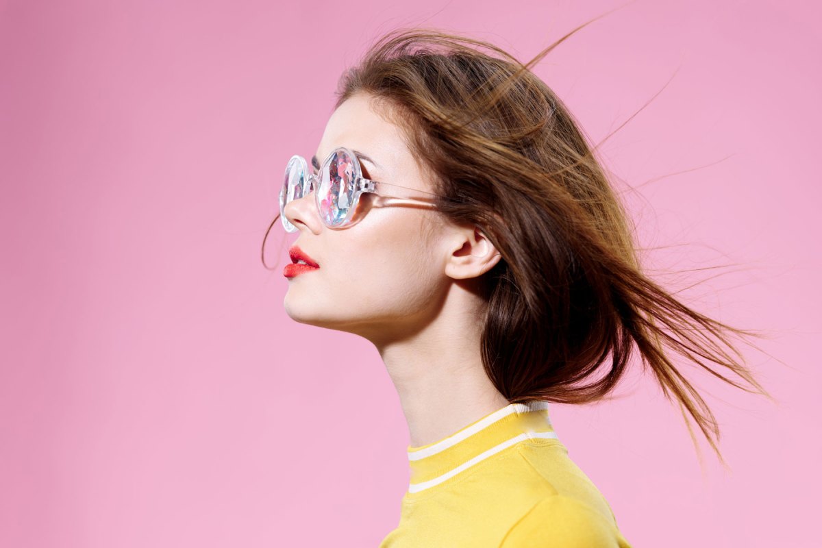 Frau mit Sonnenbrille vor einem pinken Hintergrund