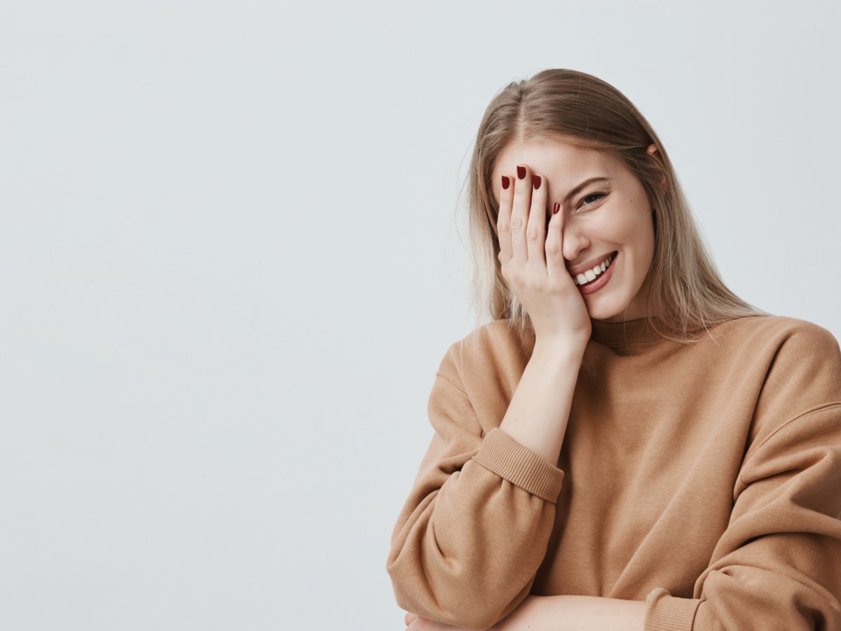 Frau, die ihre Hand vors Gesicht hält und lacht