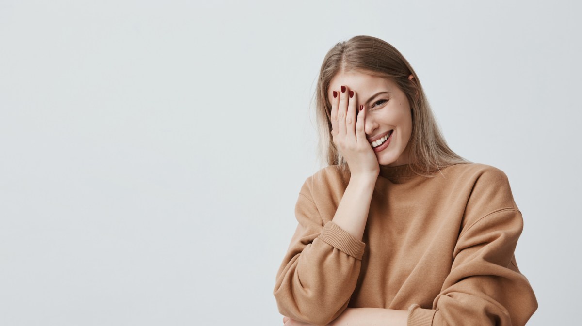 Frau, die ihre Hand vors Gesicht hält und lacht