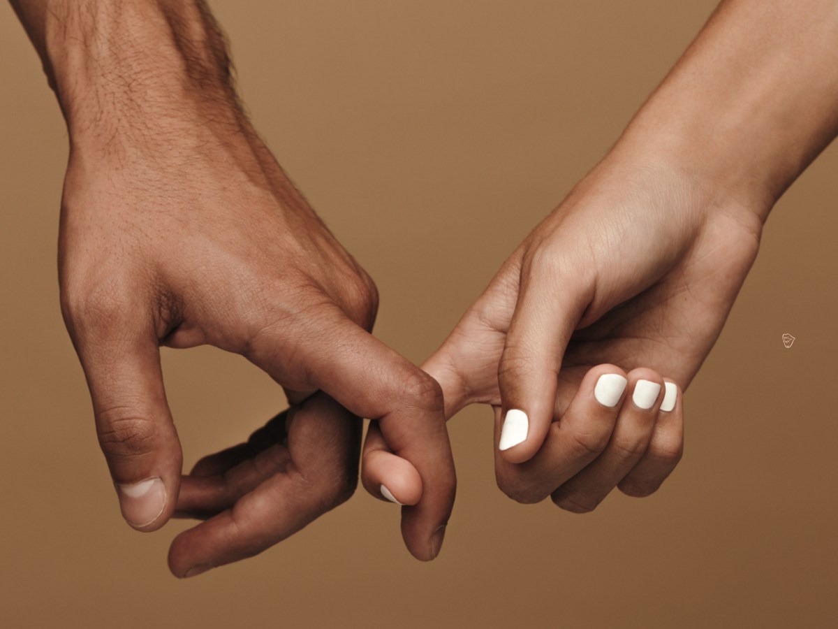 Zwei Hände vor einer braunen Wand, die sich mit dem Zeigefinger berühren