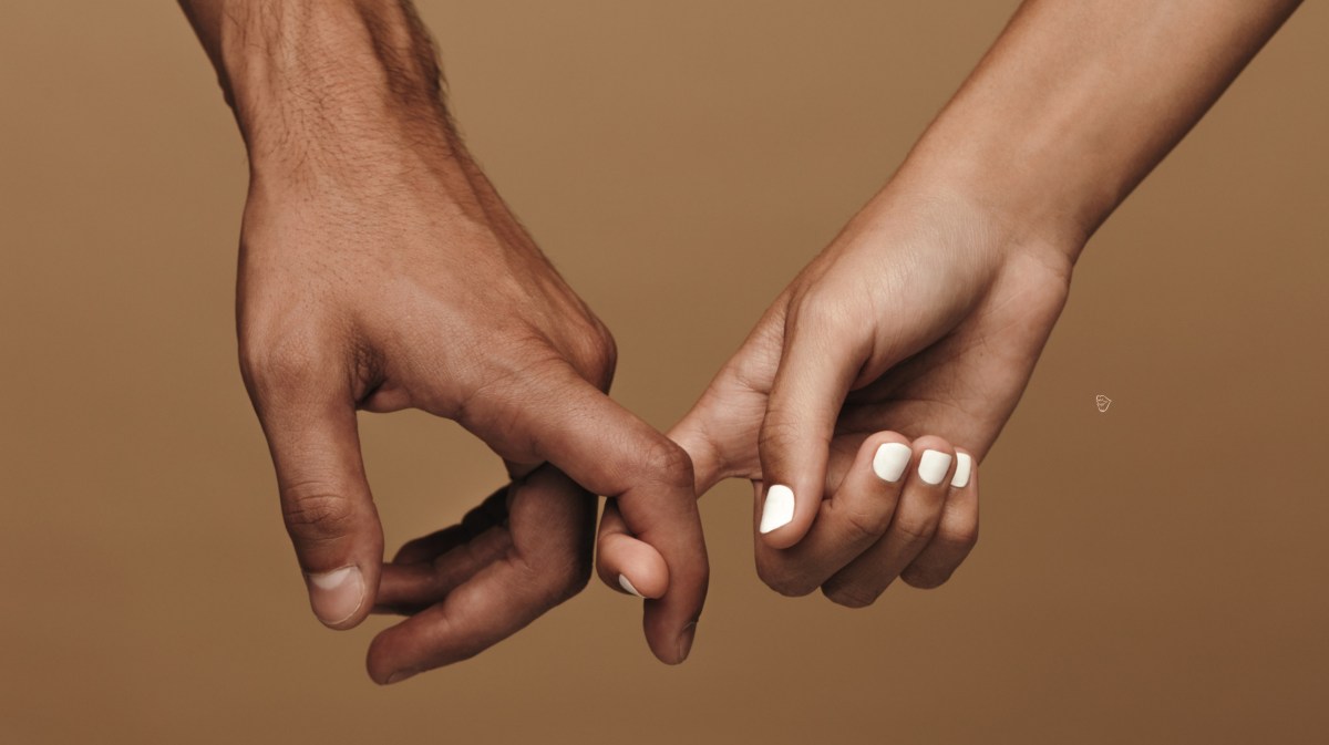 Zwei Hände vor einer braunen Wand, die sich mit dem Zeigefinger berühren