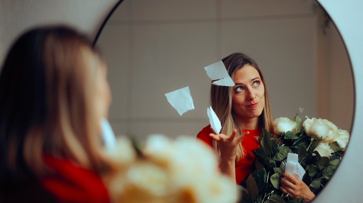 Frau in einem Spiegel, die Blumen in der Hand hält und einen Zettel zerreißt