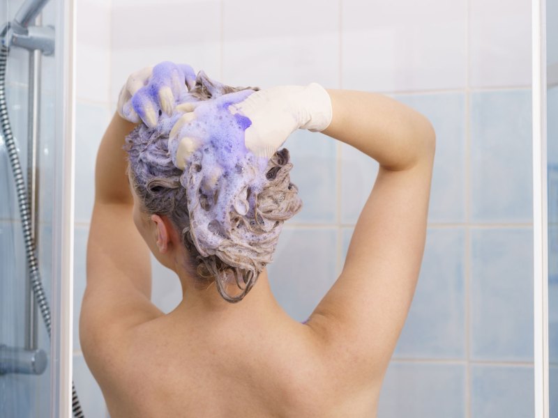 Frau, die sich mit Silbershampoo die Haare wäscht.