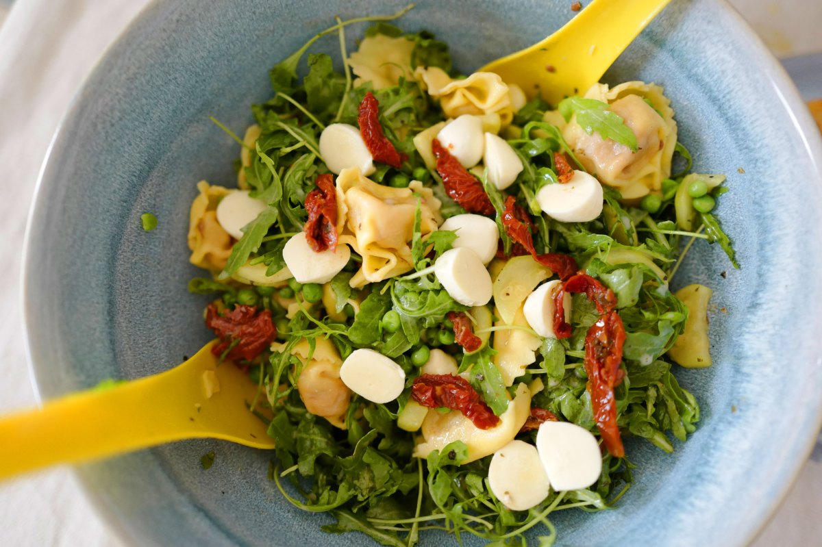 Schneller Salat zum Grillen: Tortellini Salat in blauer Schüssel mit gelbem Salatbesteck