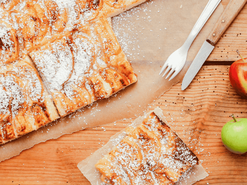 Apfelkuchen vom Blech, liegt auf Backpapier.