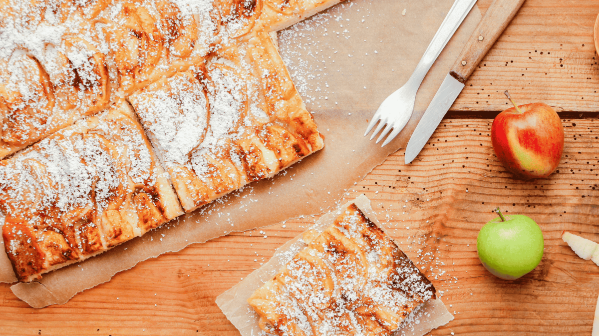 Apfelkuchen vom Blech, liegt auf Backpapier.