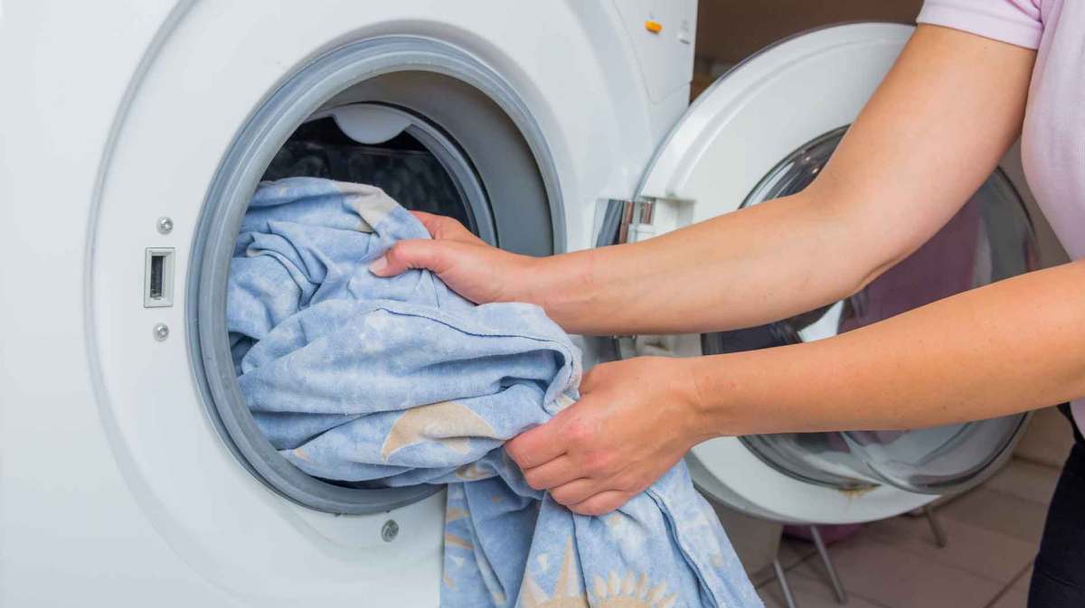 Frau wirft Wäsche in die Waschmaschine.