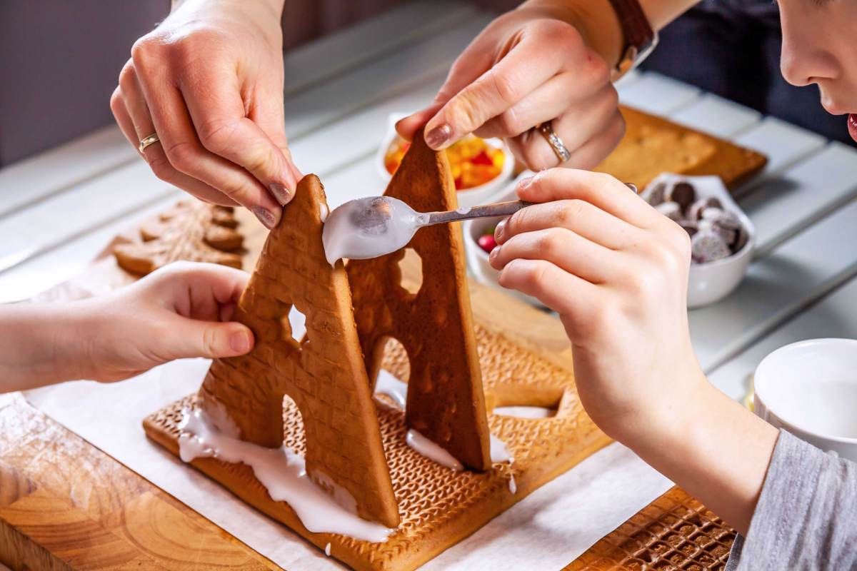 Familie baut gemeinsam ein Lebkuchenhaus.