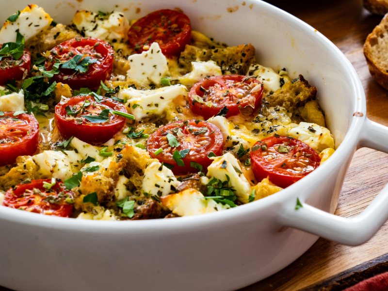 Brotauflauf mit Tomate, Brot und Mozzarella in einer weißen Form.