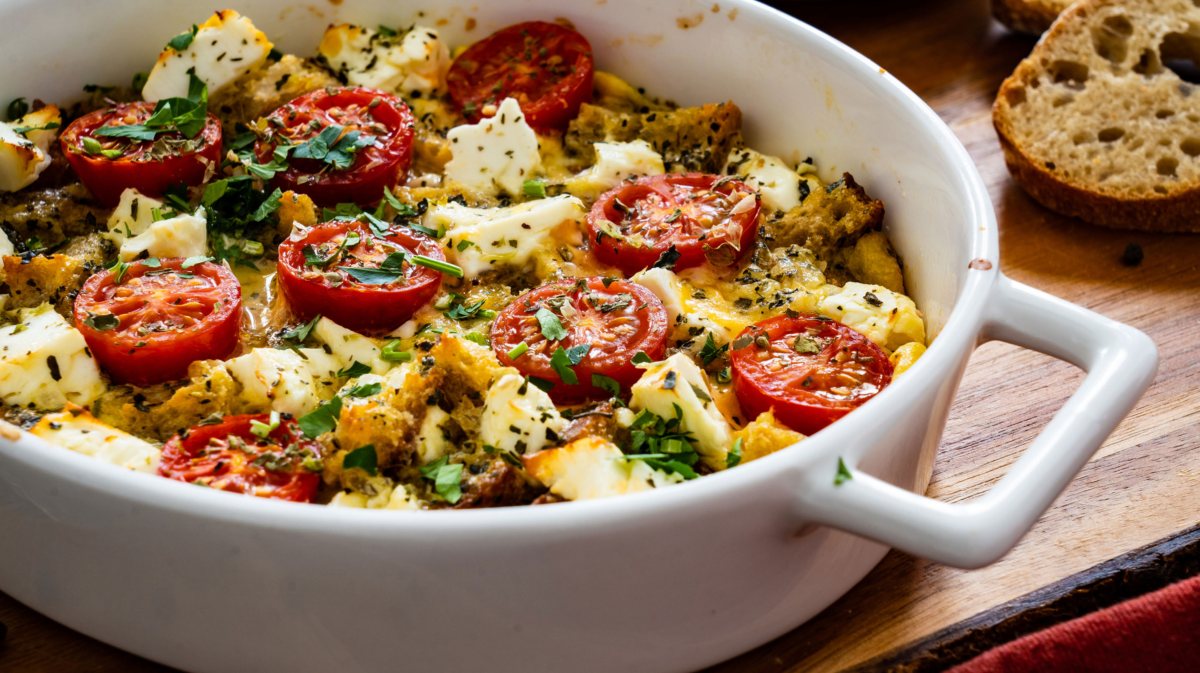 Brotauflauf mit Tomate, Brot und Mozzarella in einer weißen Form.