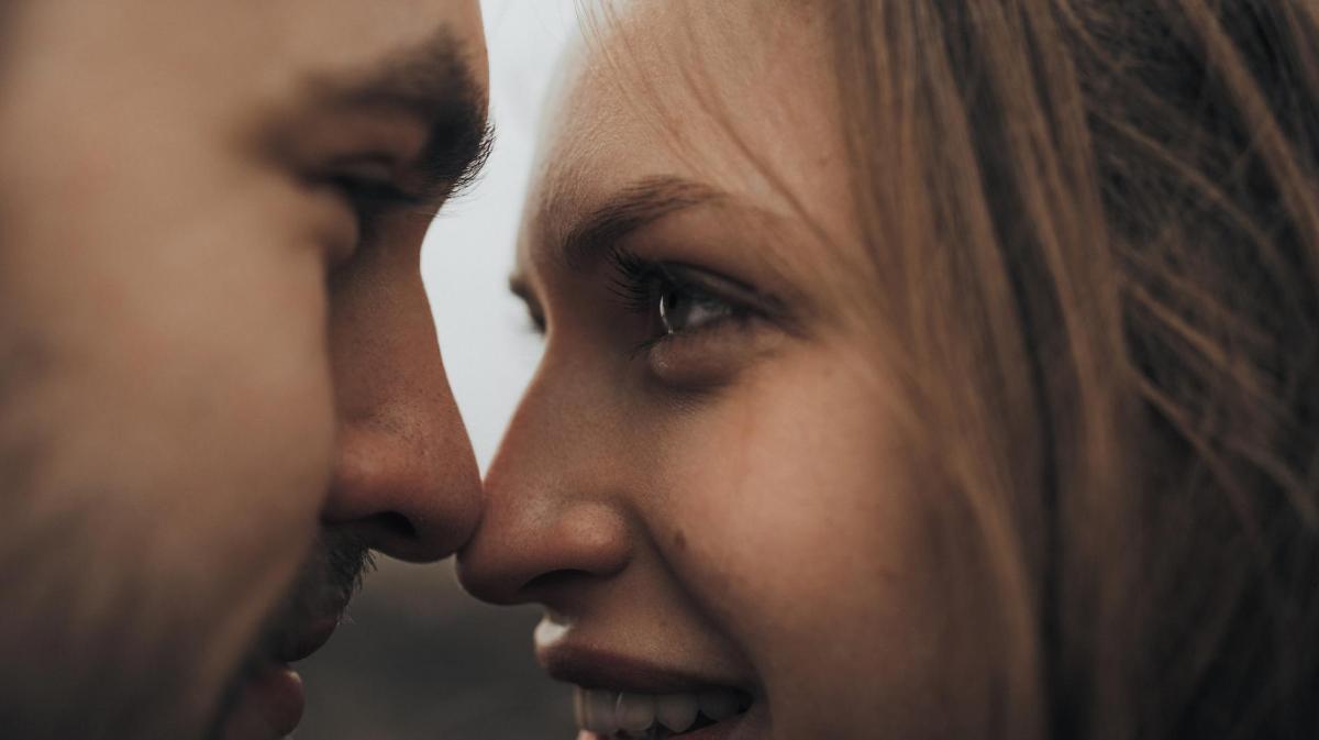 Nahaufnahme einer Frau und eines Mannes, die ganz nah voreinander stehen und sich fast küssen.