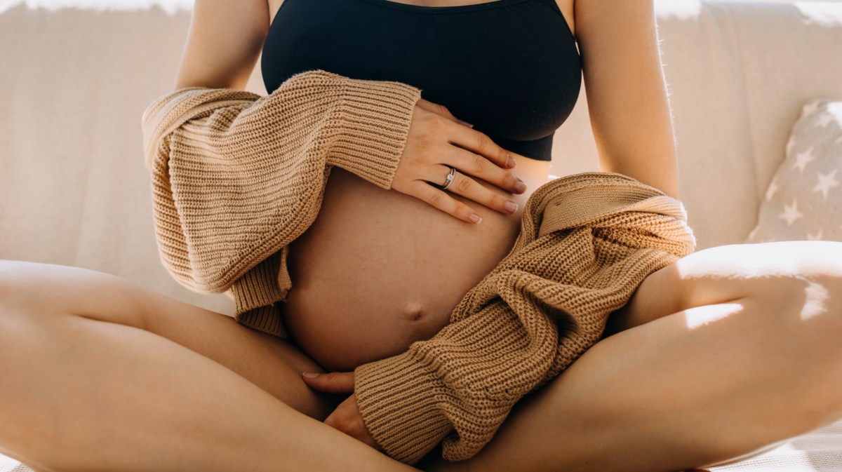 Schwangere Frau, die ihren Bauch liebevoll umarmt