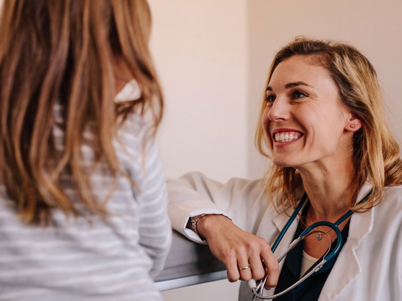 Ärztin lächelt ihre junge Patientin an.