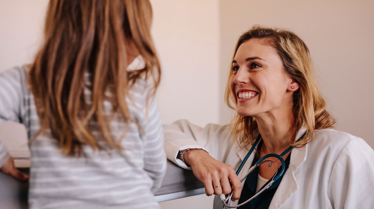 Ärztin lächelt ihre junge Patientin an.