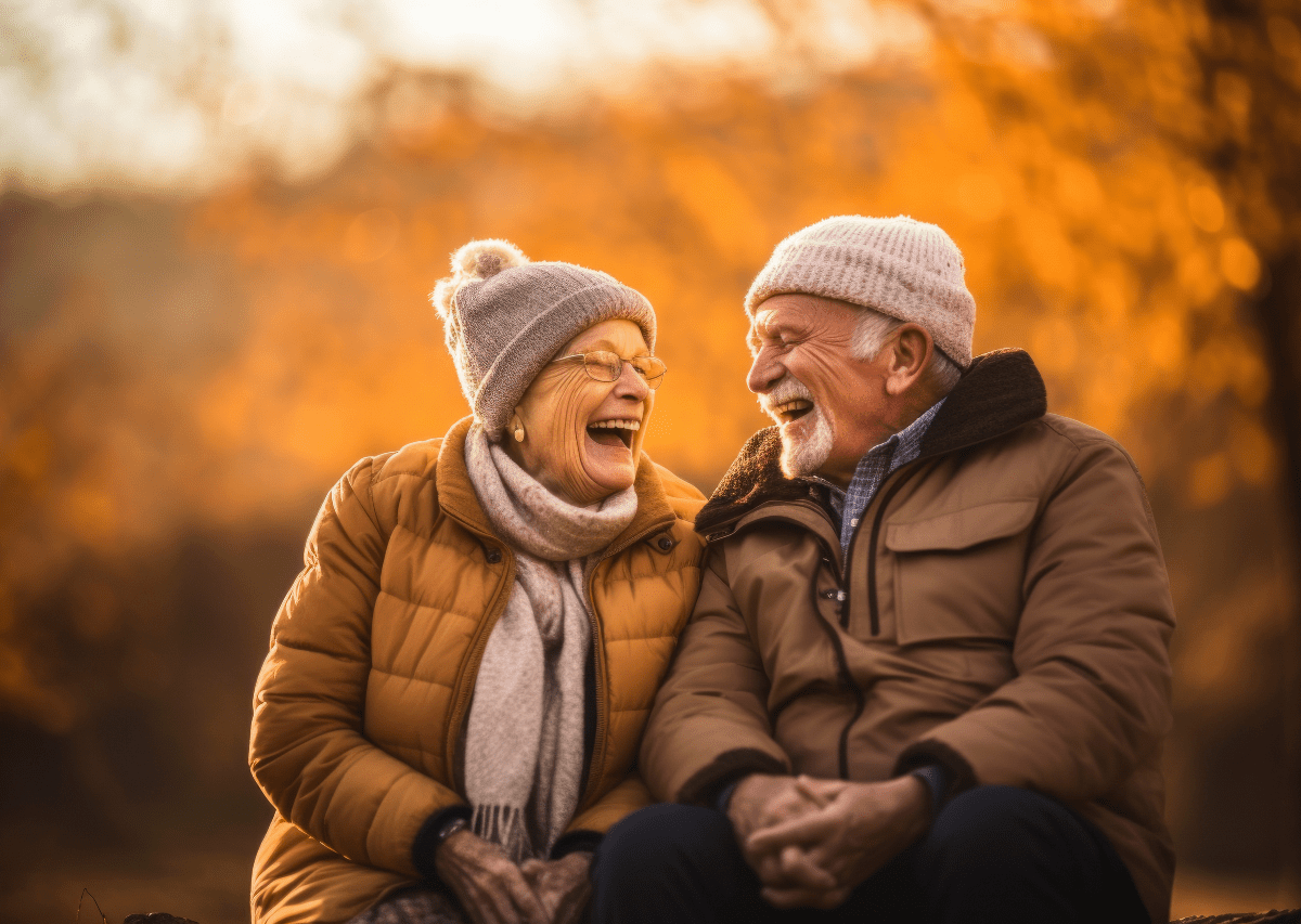 Oma und Opa auf einer Bank im Wald, die sich gegenseitig anlachen