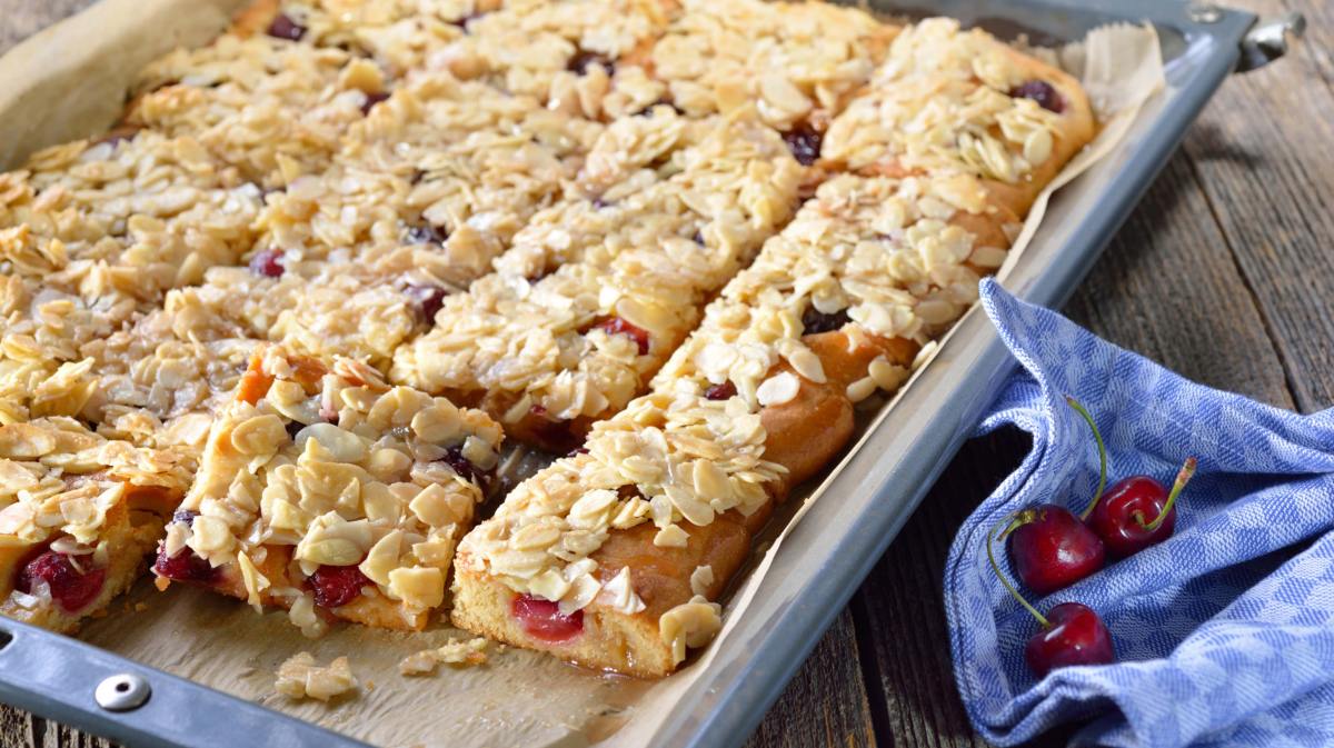 Butterkuchen mit Kirschen und Mandeln auf Backblech.