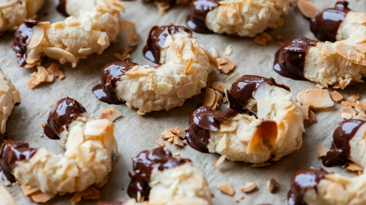 Mandelhörnchen mit Schokoenden auf einem Backblech.