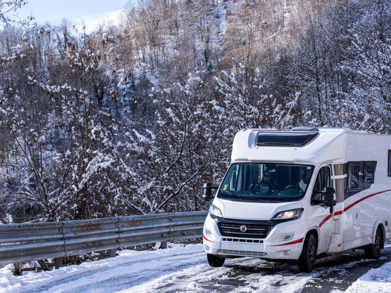 Wohnmobil auf verschneiter Straße in Winterlandschaft