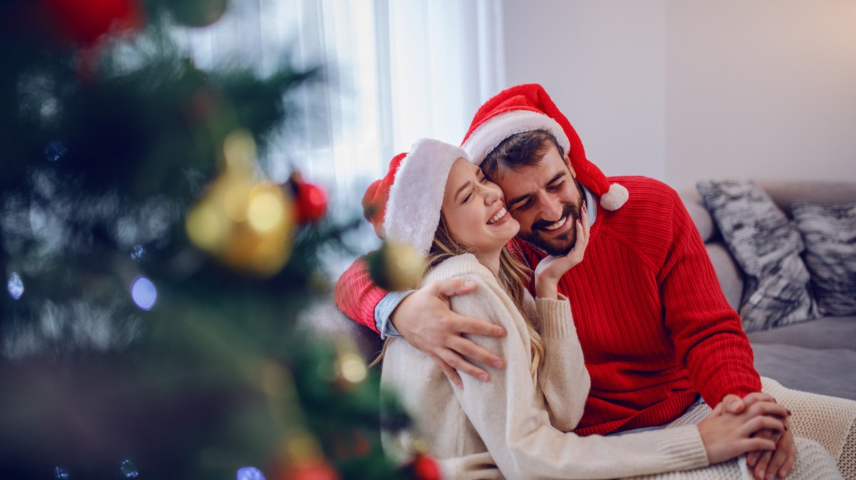 Paar an Weihnachten neben Weihnachtsbaum