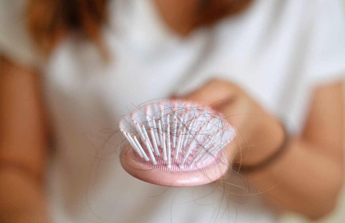 Eine Frau hält eine Haarbürste in der Hand