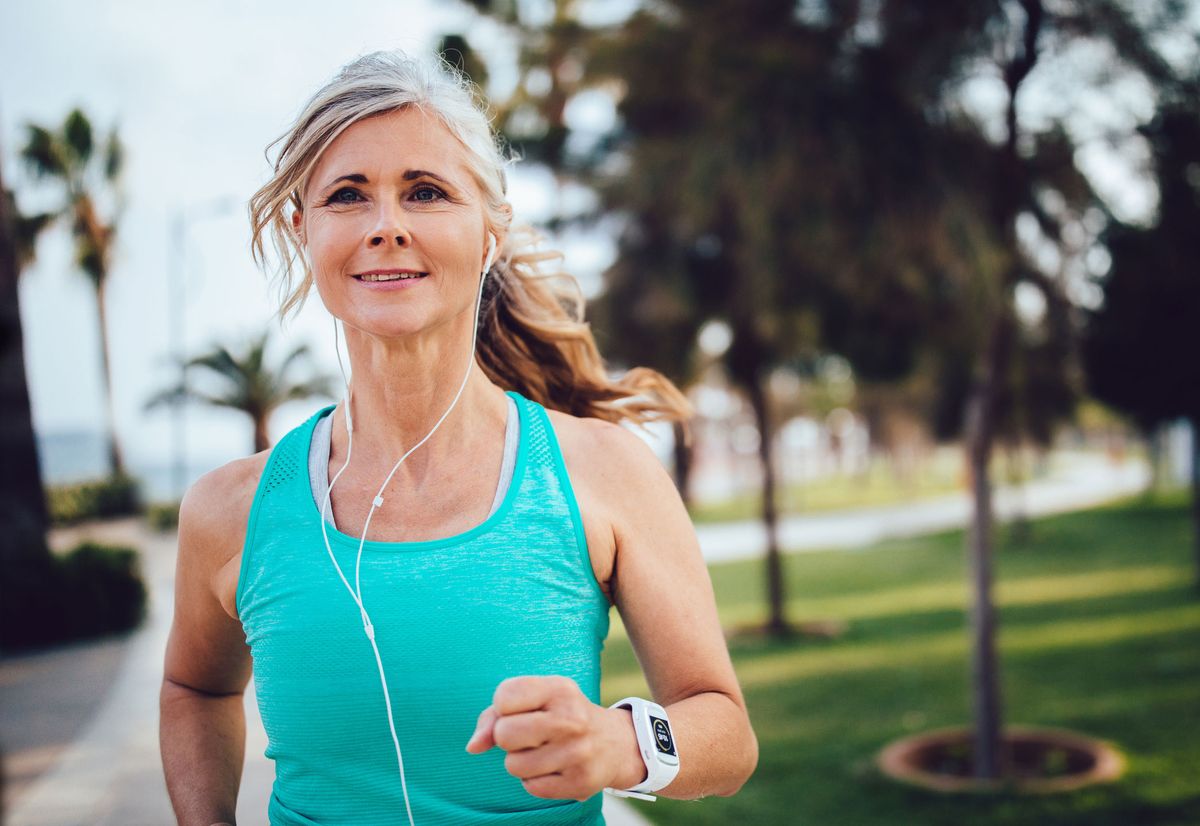 Frau mittleren Alters ist draußen joggen.