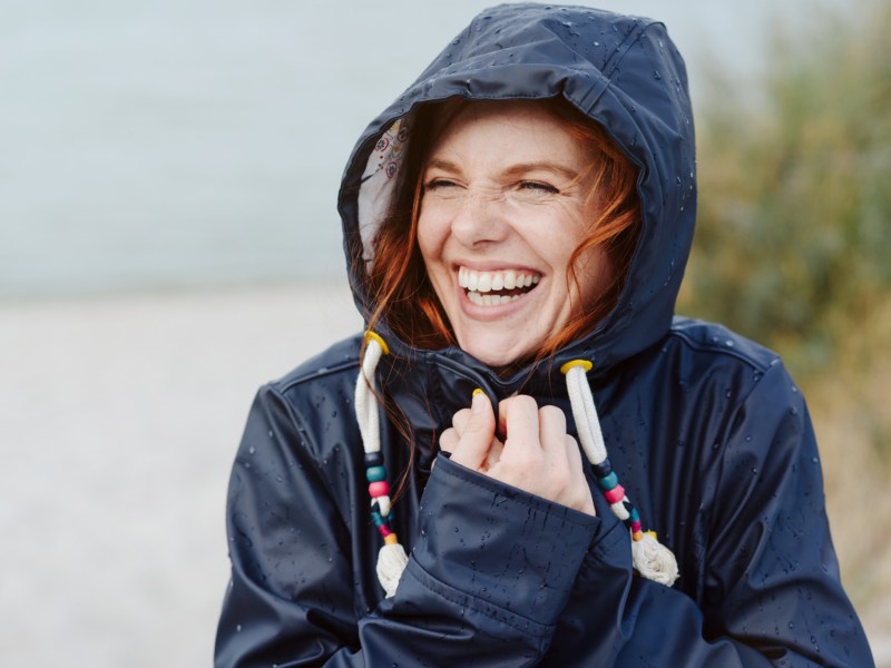 Frau mit Regenjacke lächelt.