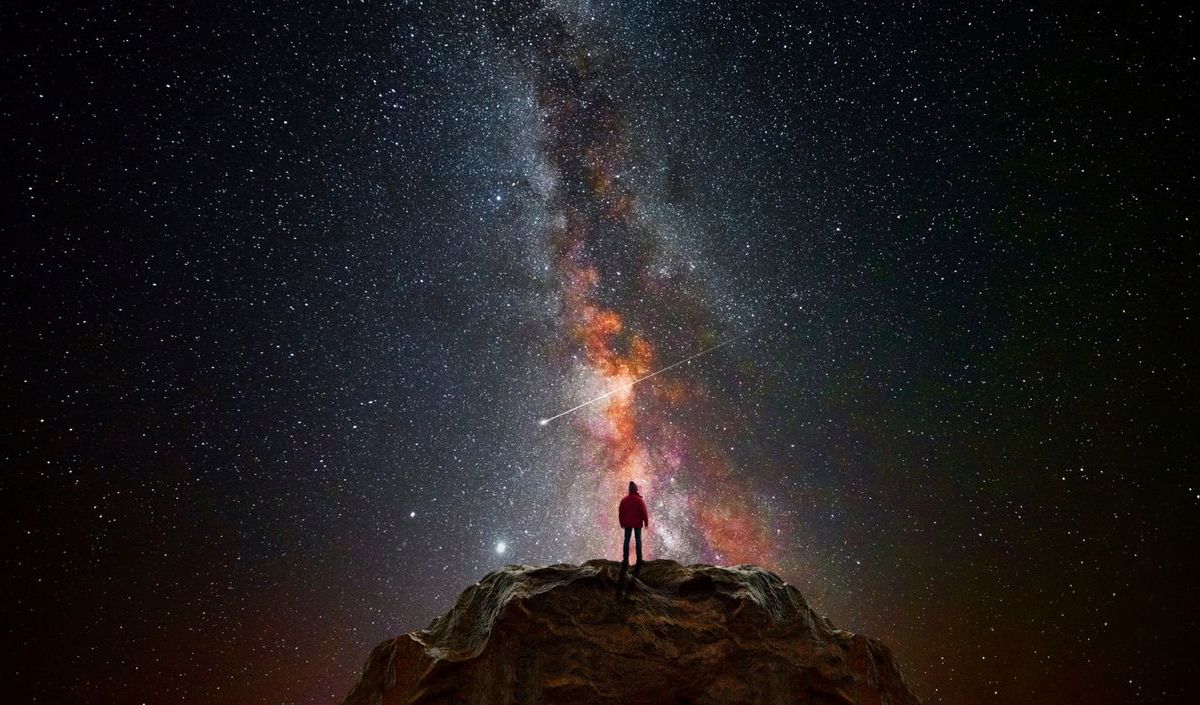 Frau schaut in den Sternenhimmel auf einem Berg 