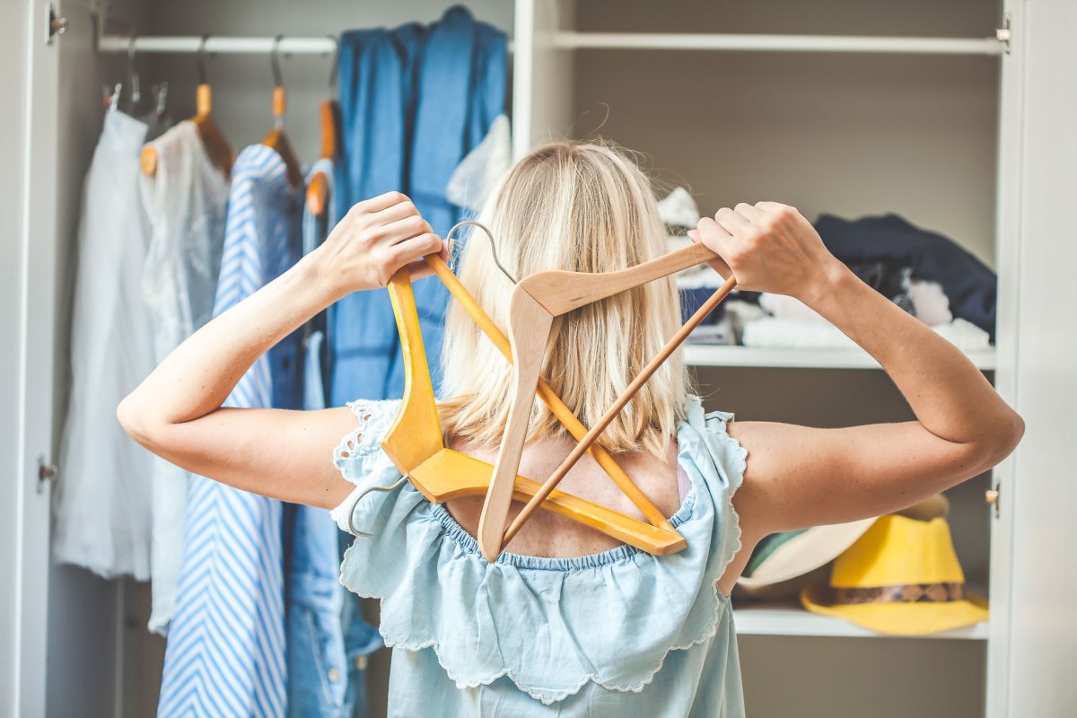 Frau, die vor ihrem vollen Kleiderschrank steht