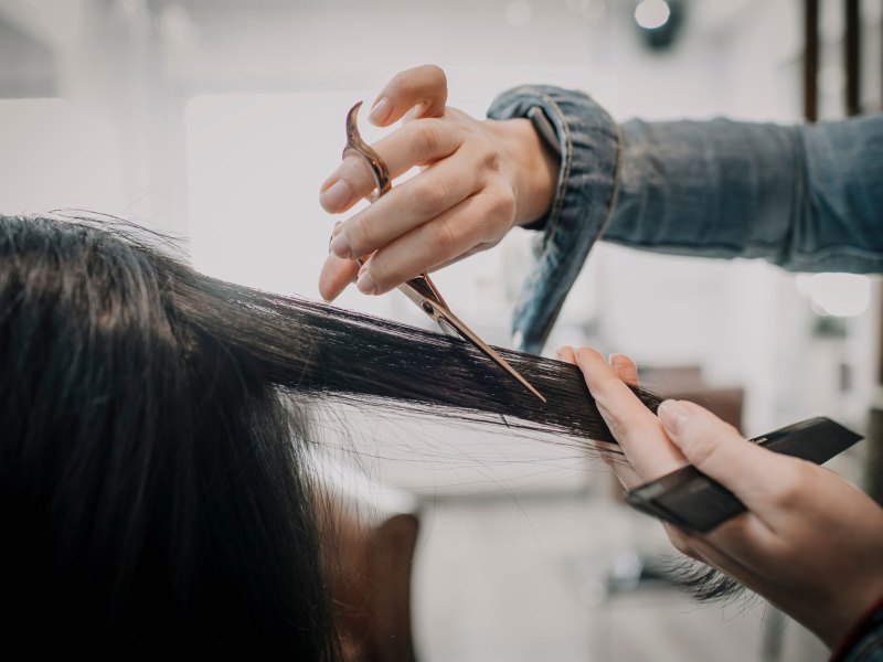 Frisörin, die gerade lange Haare kurz schneidet.