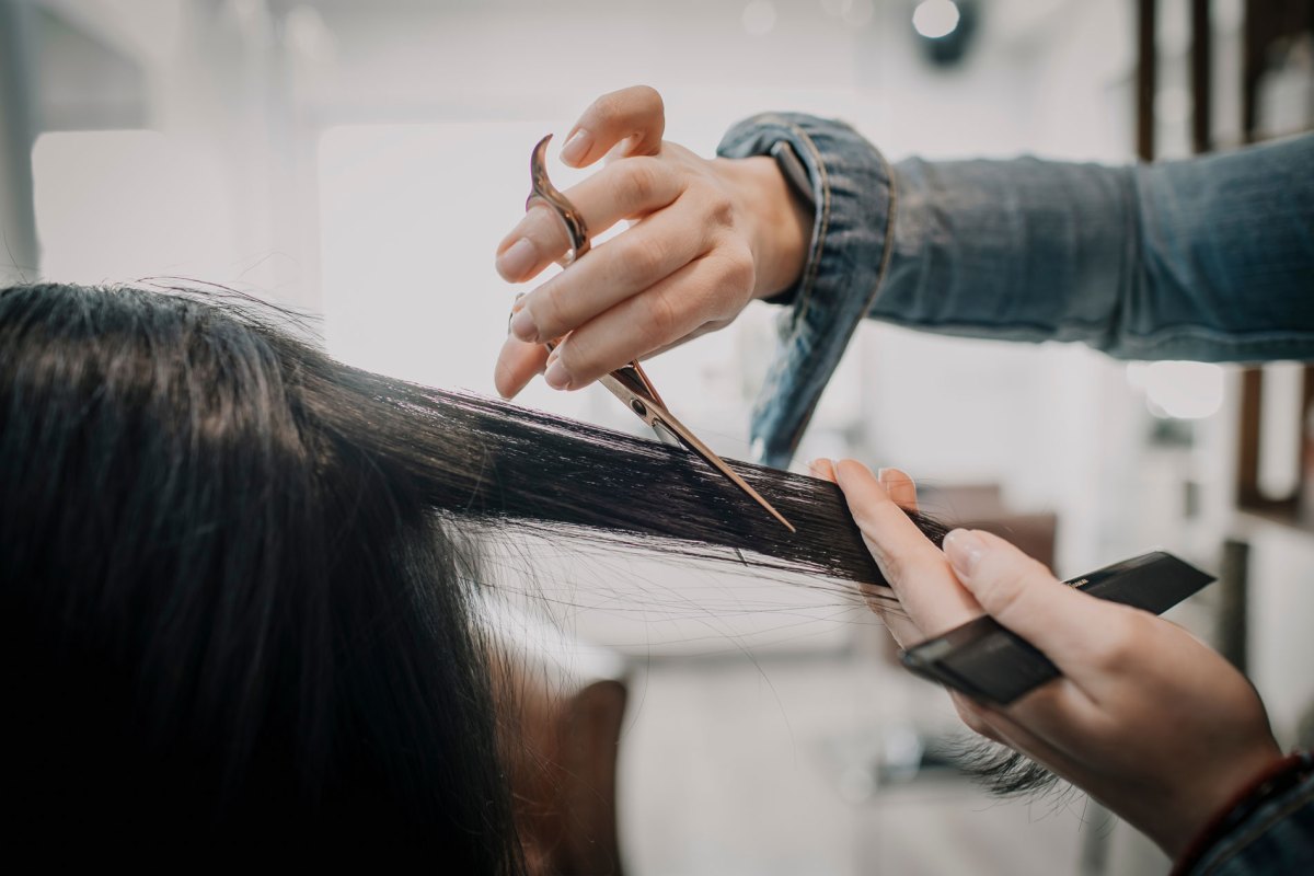 Frisörin, die gerade lange Haare kurz schneidet.