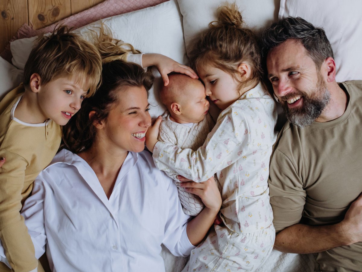 Fünfköpfige Familie liegt zusammen im Bett.