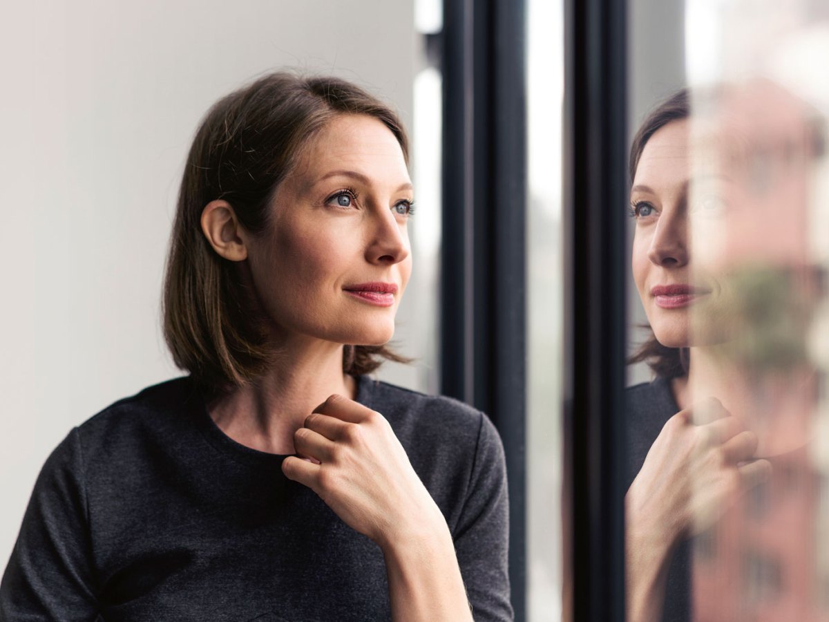 Frau schaut traurig aus dem Fenster