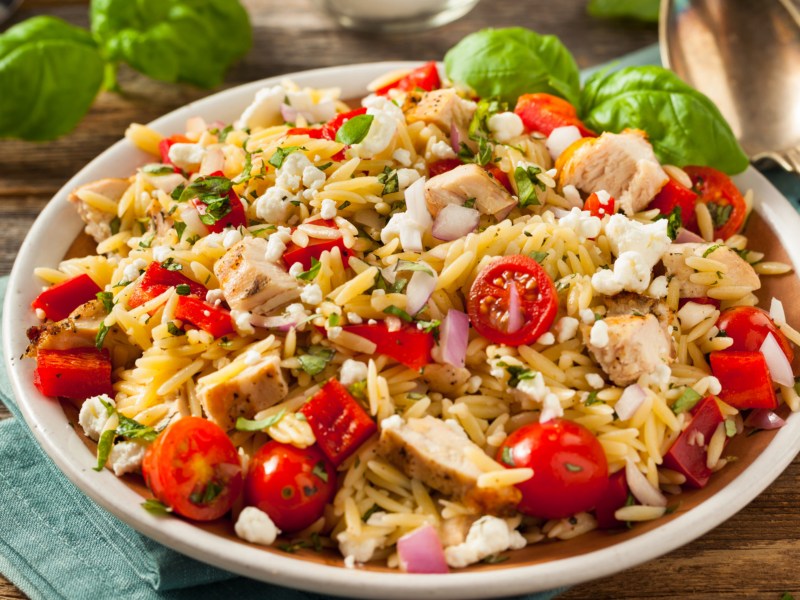 Orzo Salat mit Tomaten und Hähnchen in großer Schüssel.