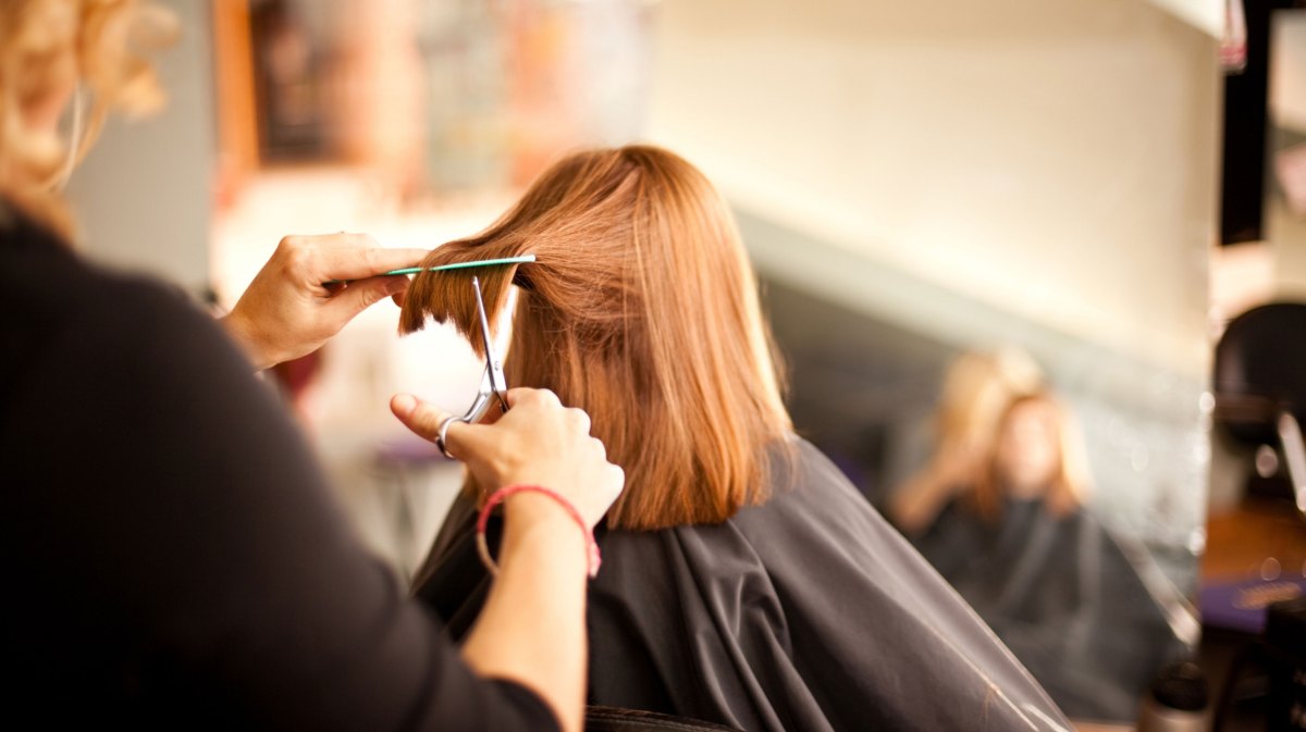 Frau lässt sich von Friseurin die Haare schneiden