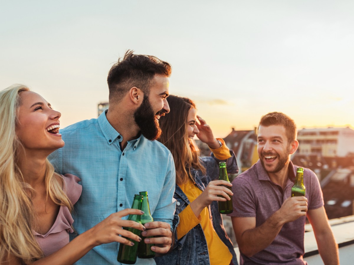 Freunde stehen gemeinsam auf Balkon im Sonnenuntergang