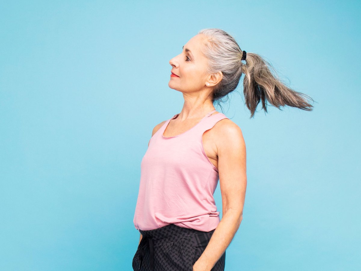 Frau mit 50 vor einer blauen Wand.