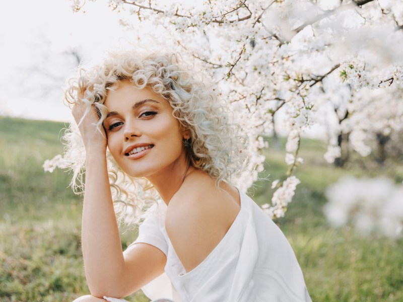 Blonde Frau zwischen weißen Blüten eines Baums