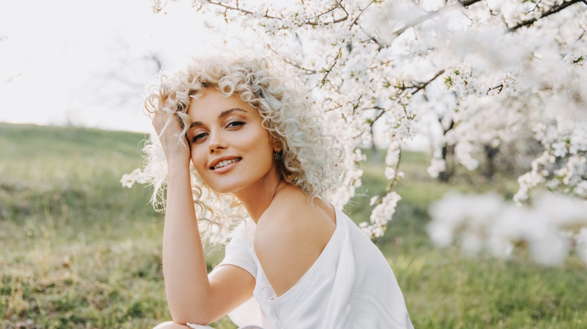 Blonde Frau zwischen weißen Blüten eines Baums