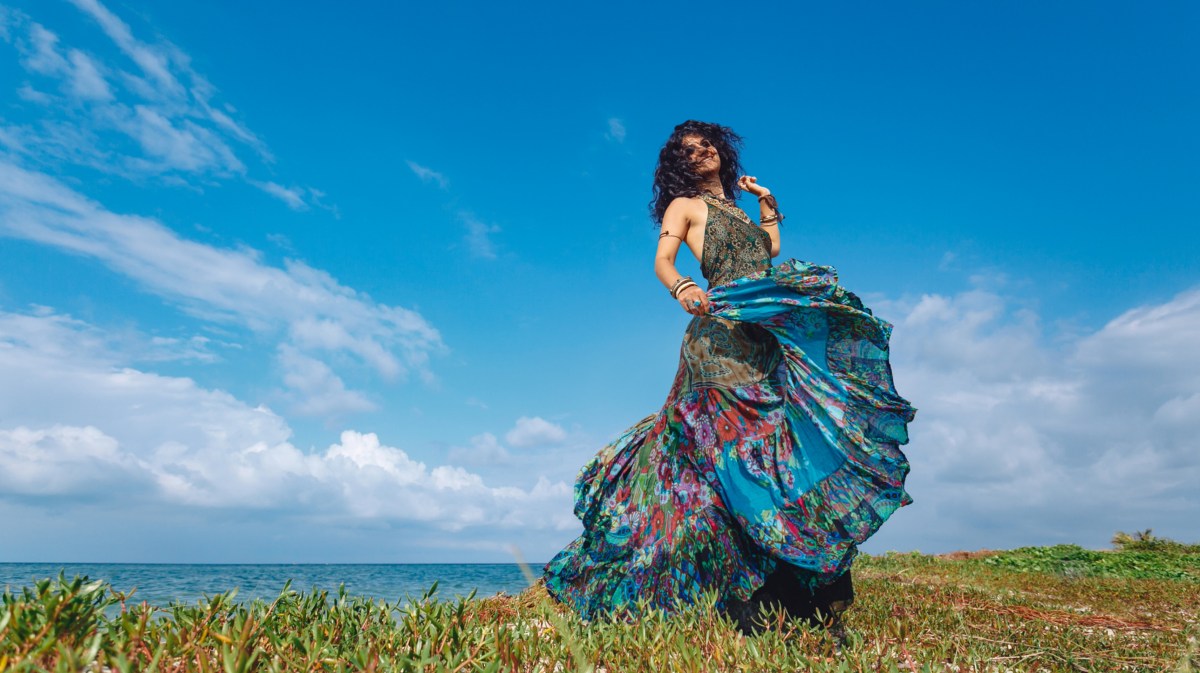 Frau tanzt in langem blauen Kleid auf einem Feld