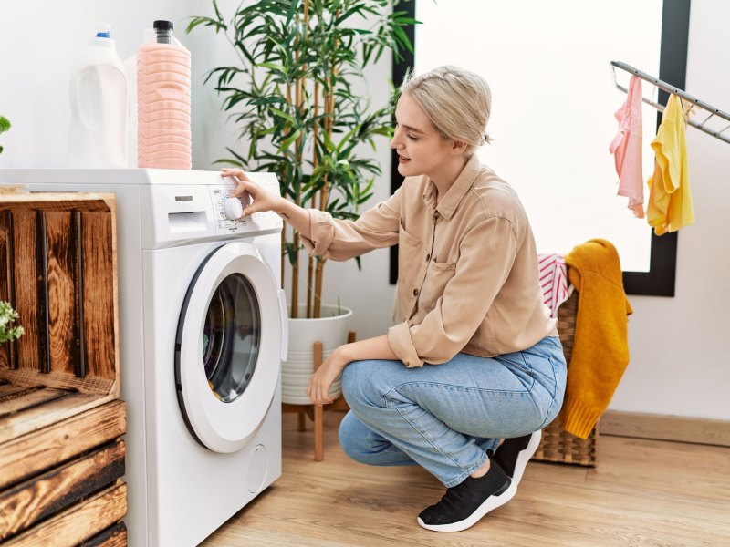Frau, die gerade die Waschmaschine anmacht