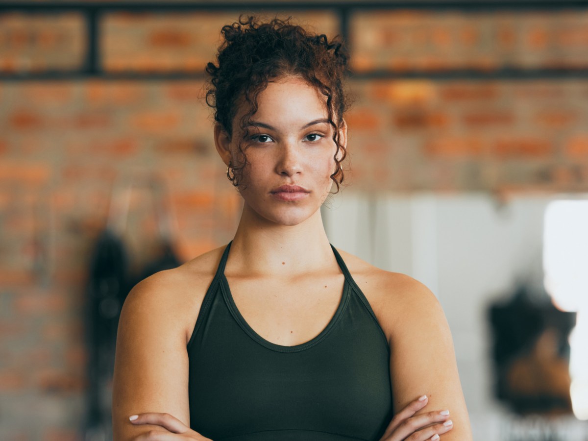 Frau im Fitnessstudio mit eingeschränkten Armen und ernstem Blick