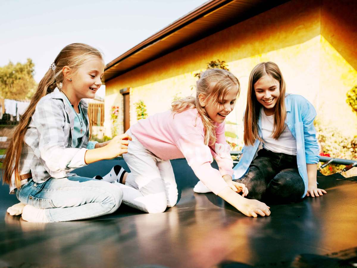 Drei Mädchen auf einem Trampolin, das ganz in der Nähe ihres Wohnhauses steht.