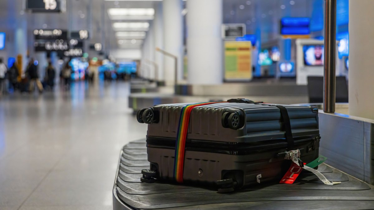 Grauer Koffer auf Gepäckband am Flughafen