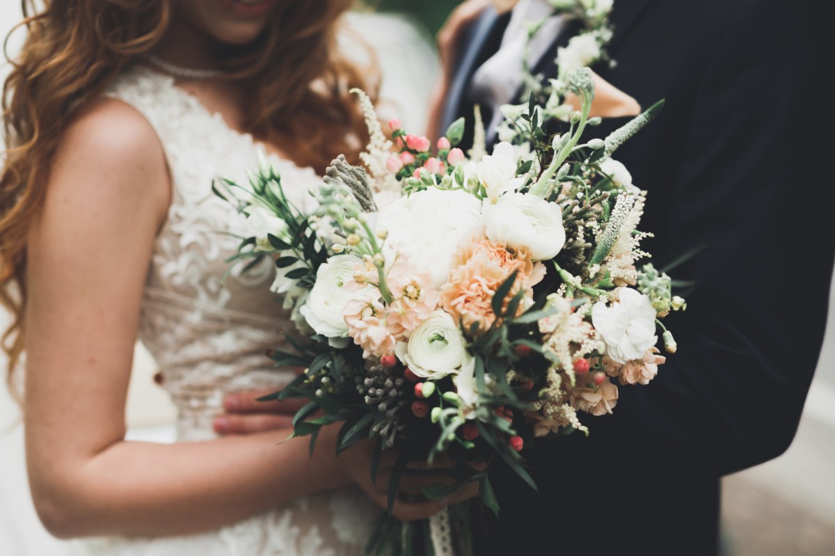 Hochzeitspaar bei der Hochzeit mit Blumenstrauß im Mittelpunkt.