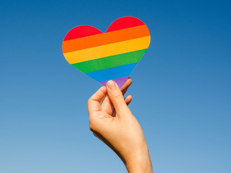 Hand hält Pride Flagge in Herzform