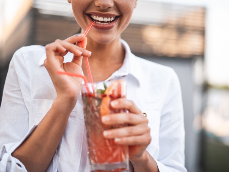 Frau mit einem Getränk in der Hand lächelt